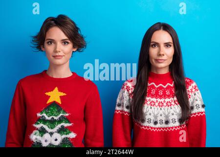 Foto di due adorabili ragazze sorelle che guardano con la macchina fotografica indossano un vestito tradizionale dell'anno nuovo, sfondo blu isolato Foto Stock