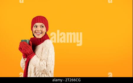 I guanti in maglia indossano una tazza di caffè su sfondo giallo Foto Stock