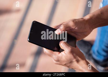 Immagine ravvicinata delle mani di un giovane che usa uno smartphone Foto Stock