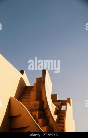 Un giovane adulto si trova in cima a una scala, guardando in basso un altro giovane adulto, che è seduto in fondo alle scale Foto Stock