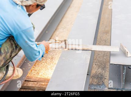 Lavoratore che taglia trave metalliche con torcia in acetilene in cantiere. Foto Stock