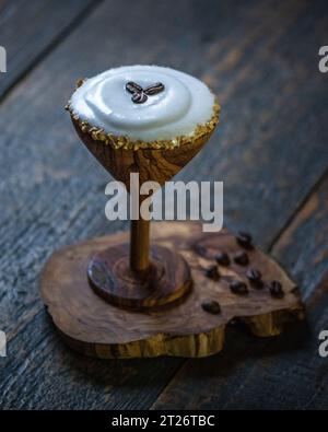 Cocktail di caffè con chicchi di caffè con sfondo in legno. Martini espresso serviti in una tazza di legno d'oliva Foto Stock
