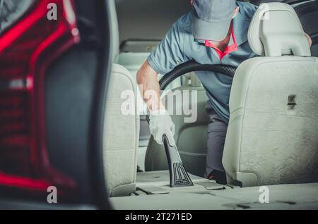 Addetto all'assistenza della concessionaria caucasica negli anni '40 pulizia del veicolo con l'uso di aspirapolvere. Tema del settore automobilistico. Foto Stock