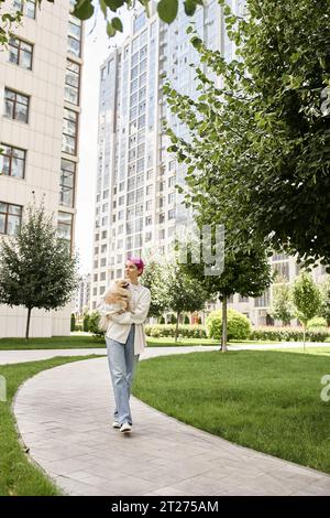 una donna alla moda con un piccolo cane di razza in mano che cammina per strada e per lo stile di vita cittadino Foto Stock