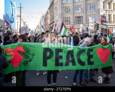 La donna tiene un grande striscione verde "pace" a Oxford Circus, nel centro di Londra, durante la marcia/protesta pro Palestina del 14 ottobre 2023. Foto Stock