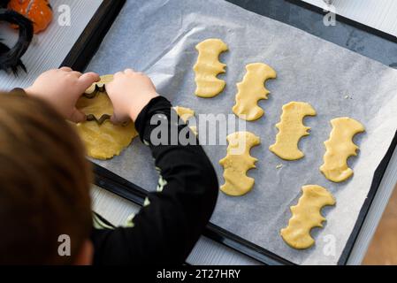 ragazzo vestito da scheletro che prepara biscotti di halloween a casa. Prepariamo halloween Foto Stock
