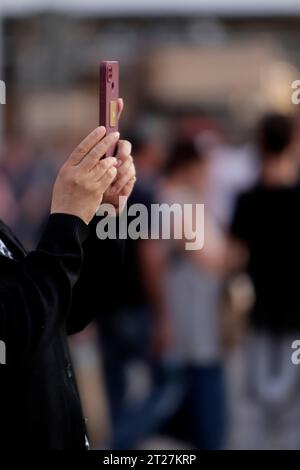 le mani di una donna con il cellulare che fa una foto in città Foto Stock