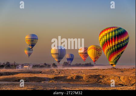 Mongolfiere che iniziano il processo di atterraggio, in collaborazione con le rispettive squadre di inseguimento, dopo i voli all'alba del mattino presto Foto Stock