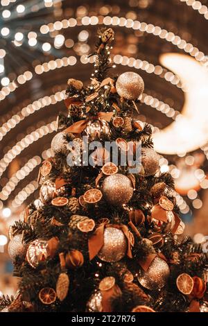 Albero di Natale decorato con arance secche, mandarini, coni di pino e palline di Natale dorate e lucenti. Dettagli magici. Stagione delle vacanze invernali nel periodo delle festività natalizie Foto Stock