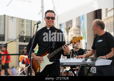 Una band, tra cui un prete cattolico, che tiene un concerto durante le Giornate mondiali della gioventù 2023 a Lisbona, Portogallo. Il concerto si è svolto vicino alla chiesa di St Roch. Foto Stock