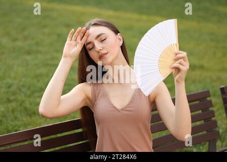 Donna con ventola a mano che soffre di calore all'aperto Foto Stock