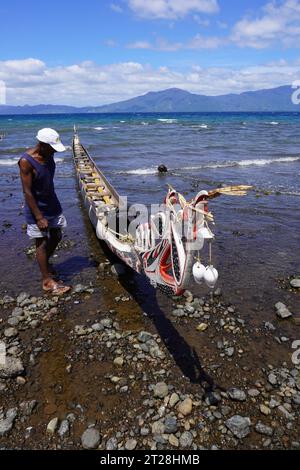 Uomo e canoa da guerra sulle rive di Alotau, Papua nuova Guinea Foto Stock