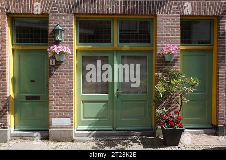 Facciata esterna di una tipica casa in mattoni con porte e finestre verdi dipinte ad Haarlem, Olanda, Paesi Bassi Foto Stock