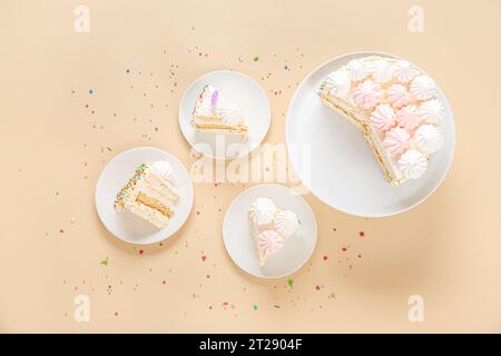 Piatti con pezzi di deliziosa torta di compleanno su sfondo beige Foto Stock