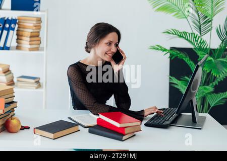 Bella donna d'affari che parla al telefono in ufficio durante l'istruzione di formazione in ufficio Foto Stock