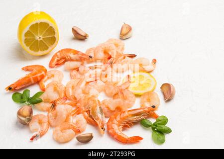 Gamberi, gamberi tigre sparsi su sfondo bianco. Foglie di basilico verde, limone, aglio e pepe. Cibo delizioso e appetitoso. Vista dall'alto Foto Stock