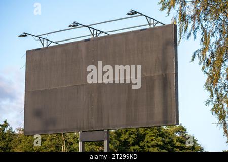 Un cartellone marrone con proiettori sul lato della strada Foto Stock