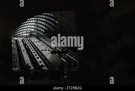 Londra, Inghilterra - 16 ottobre 2023 - persone in sella alle scale mobili all'interno della stazione della metropolitana di Canary Wharf. È una stazione sulla Jubilee Line Foto Stock