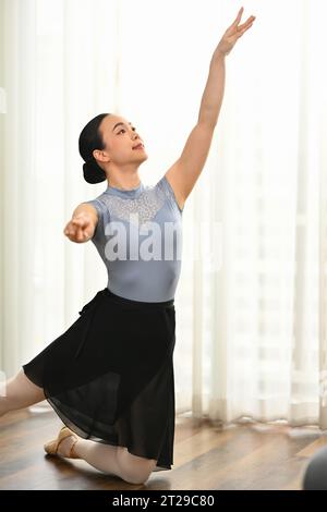 Giovane donna impegnata che pratica il balletto a casa. Concetto di danza, arte, educazione e flessibilità Foto Stock