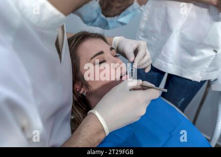 Una dentista donna cura i denti di un paziente. Il dentista effettua una pulizia professionale dei denti di una giovane paziente nello studio dentistico. Foto Stock