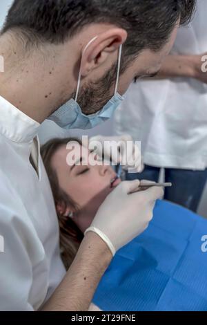 Una dentista donna cura i denti di un paziente. Il dentista effettua una pulizia professionale dei denti di una giovane paziente nello studio dentistico. Foto Stock