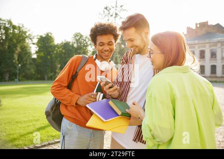 Gruppo di studenti adolescenti che ridono mentre guardano video divertenti sul cellulare Foto Stock