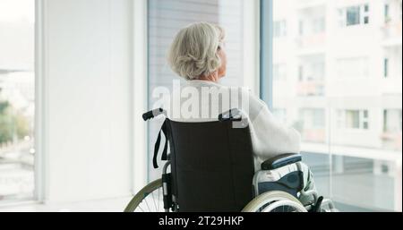 Pensiero, donna in sedia a rotelle e finestra in casa di cura o persona con disabilità in ospedale con depressione o salute mentale. Depresso, triste Foto Stock