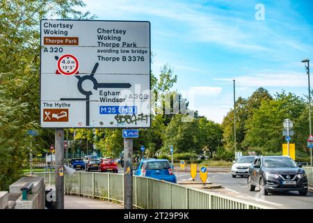 Un grande cartello stradale alla fine del Staines Bridge a Staines-upon-Thames, Surrey, Regno Unito fornisce indicazioni per i conducenti che entrano in una rotatoria. Foto Stock