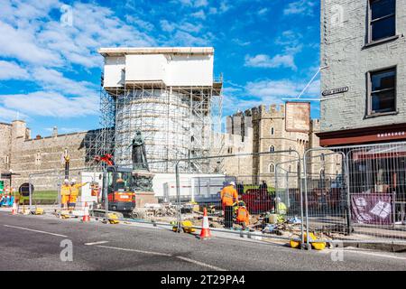 Lavori stradali all'esterno del Castello di Windsor intorno alla statua di bronzo della Regina Vittoria. L'area è recintata mentre gli operai scavano la strada. Foto Stock