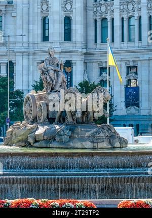 Madrid, Spagna, Fontana di Cibele, una scultura iconica nel quartiere del centro. Una bandiera dell'Ucraina onda sullo sfondo. Foto Stock