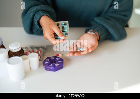 Donne che organizzano il suo farmaco in un dispenser di pillole. donna che prende pillole dalla scatola. Sanità e concetto con i farmaci. Medicinali sul tavolo Foto Stock