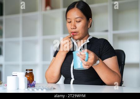 Primo piano donna che tiene la pillola in mano con l'acqua che si sente male. donna che sta per prendere antidolorifico da mal di testa, antidolorifico, assistenza sanitaria, medicina Foto Stock