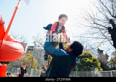 Giovane uomo padre Afro Latino venezuelano, felice di cercare suo figlio nel parco, lo solleva in aria, concetto di famiglia, spazio copia. Foto Stock
