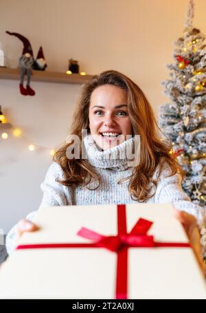 Stagione delle donazioni. Giovane donna felice che riceve una scatola regalo di Natale. Foto Stock
