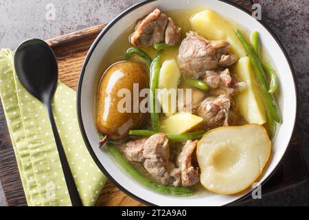 Stufato di agnello con pere, patate, fagioli verdi in una salsa piccante da vicino in un recipiente su una tavola di legno. vista superiore orizzontale dall'alto Foto Stock