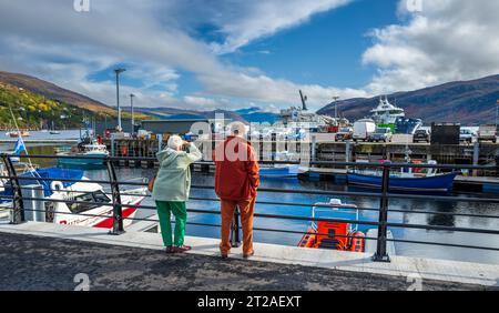 Un paio sulla riva di Ullapool, altopiani scozzesi a guardare le barche Foto Stock