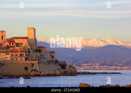 Storica città costiera di Antibes con vista sulle montagne al tramonto nel sud della Francia che mostra le pareti del mare e i bastioni con le montagne innevate Foto Stock