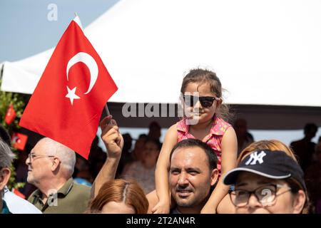 Izmir, Turchia, 9 settembre 2023: Un momento commovente che cattura una ragazza di 8-9-year-Old con gli occhiali da sole, appollaiata sulle spalle di suo padre, salutando Foto Stock