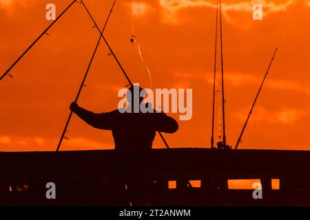 Isola di Palms, Stati Uniti. 18 ottobre 2023. Un pescatore sagomato dall'alba si muove intorno a un groviglio di canne da pesca sul molo Isle of Palms, il 18 ottobre 2023 a Isle of Palms, South Carolina. Crediti: Richard Ellis/Richard Ellis/Alamy Live News Foto Stock