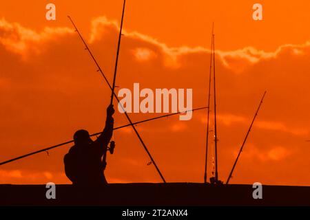 Isola di Palms, Stati Uniti. 18 ottobre 2023. Un pescatore sagomato dall'alba si muove intorno a un groviglio di canne da pesca sul molo Isle of Palms, il 18 ottobre 2023 a Isle of Palms, South Carolina. Crediti: Richard Ellis/Richard Ellis/Alamy Live News Foto Stock