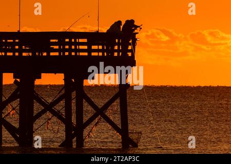 Isola di Palms, Stati Uniti. 17 ottobre 2023. Fisherman, sagomato dall'alba in un pesce del molo dell'Isola di Palms, 17 ottobre 2023 a Isle of Palms, South Carolina. Crediti: Richard Ellis/Richard Ellis/Alamy Live News Foto Stock