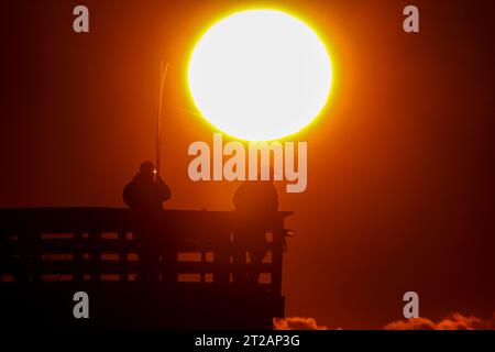 Isola di Palms, Stati Uniti. 17 ottobre 2023. Fisherman, sagomato dall'alba, aspetta di sfrecciare nel grande molo dell'Isola di Palms, il 17 ottobre 2023 a Isle of Palms, South Carolina. Crediti: Richard Ellis/Richard Ellis/Alamy Live News Foto Stock