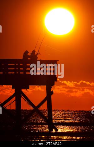 Isola di Palms, Stati Uniti. 17 ottobre 2023. Fisherman, sagomato dall'alba, aspetta di sfrecciare nel grande molo dell'Isola di Palms, il 17 ottobre 2023 a Isle of Palms, South Carolina. Crediti: Richard Ellis/Richard Ellis/Alamy Live News Foto Stock