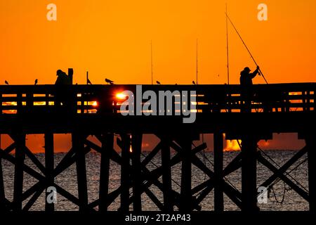 Isola di Palms, Stati Uniti. 17 ottobre 2023. Fisherman, sagomato dall'alba, aspetta di sfrecciare nel grande molo dell'Isola di Palms, il 17 ottobre 2023 a Isle of Palms, South Carolina. Crediti: Richard Ellis/Richard Ellis/Alamy Live News Foto Stock