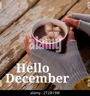 Ciao testo di dicembre con le mani di donna caucasica in guanti che tengono una bevanda di cioccolato di natale Foto Stock