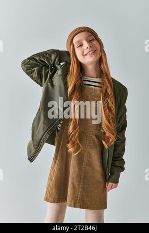 moda per bambini, ragazza allegra con i capelli lunghi e cappello in maglia in abito e giacca invernale Foto Stock