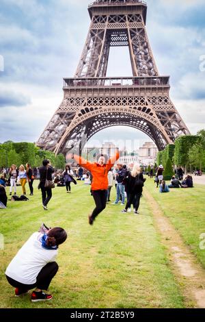 La gente si riunisce e posa per delle foto sul Champ de Mars vicino alla Torre Eiffel a Parigi, in Francia. Foto Stock