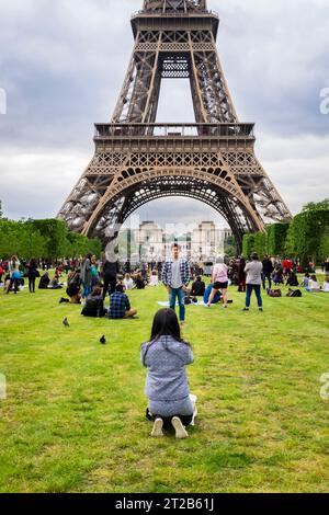 La gente si riunisce e posa per delle foto sul Champ de Mars vicino alla Torre Eiffel a Parigi, in Francia. Foto Stock