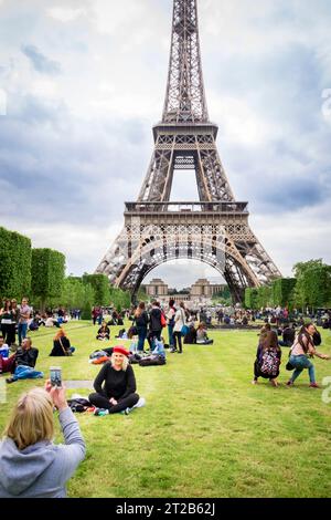 La gente si riunisce e posa per delle foto sul Champ de Mars vicino alla Torre Eiffel a Parigi, in Francia. Foto Stock