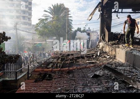 Awkar, Libano. 18 ottobre 2023. Un dimostratore porta salite in un edificio bruciato per lanciare rocce alla polizia antisommossa durante una protesta nei pressi dell'ambasciata degli Stati Uniti ad Awkar, Libano, il 18 ottobre 2023. La gente protestava contro lo sciopero israeliano all'ospedale battista di al-Ahli uccise circa 500 persone a Gaza. Diverse lesioni si sono verificate quando la polizia antisommossa ha usato un canone d'acqua e sparato gas lacrimogeni ai manifestanti, a volte urlando direttamente contro i manifestanti piuttosto che puntando in alto in aria in modo che i contenitori cadano durante la dimostrazione. Un medico ha riferito di aver curato 10 persone ferite, incl Foto Stock